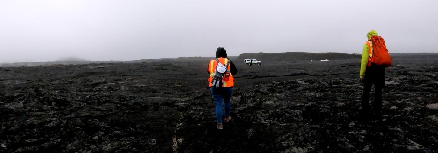 研究er walks across black Icel和ic lava flow.